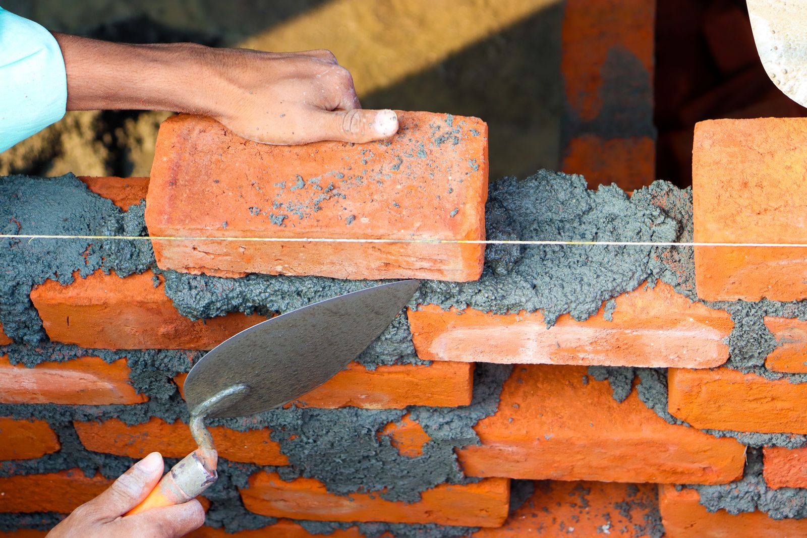 Mason laying bricks with mortar on a wall