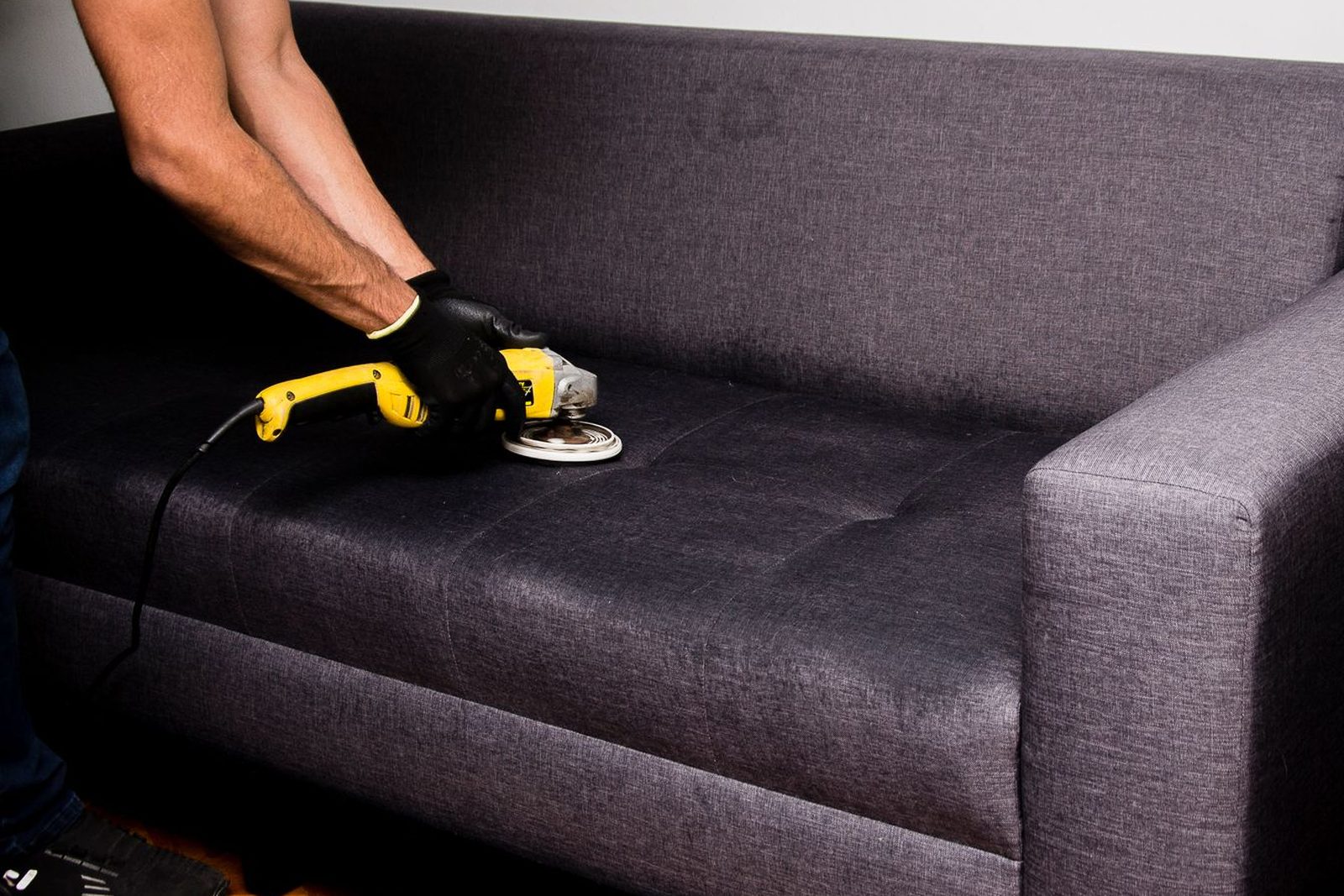 Technician cleaning a fabric sofa with a rotary upholstery machine