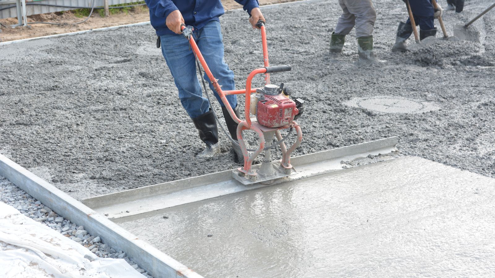 Crew screeding a freshly poured slab with a power screed
