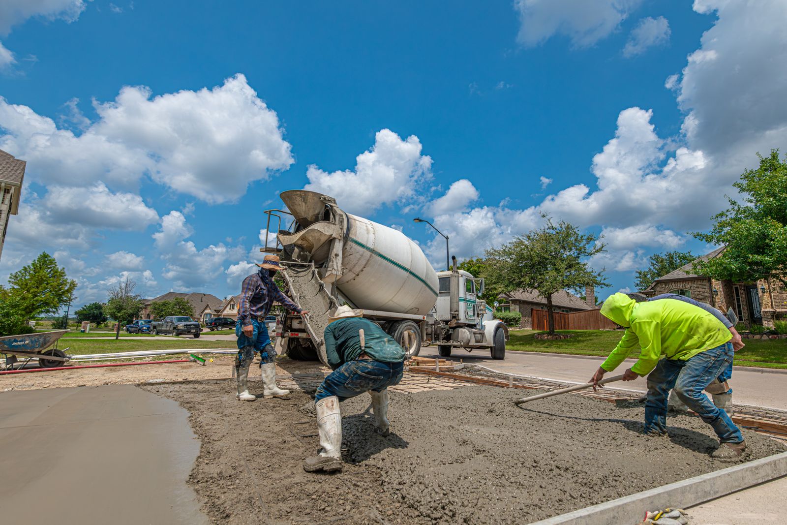 Crew pouring and spreading a concrete driveway from a mixer truck