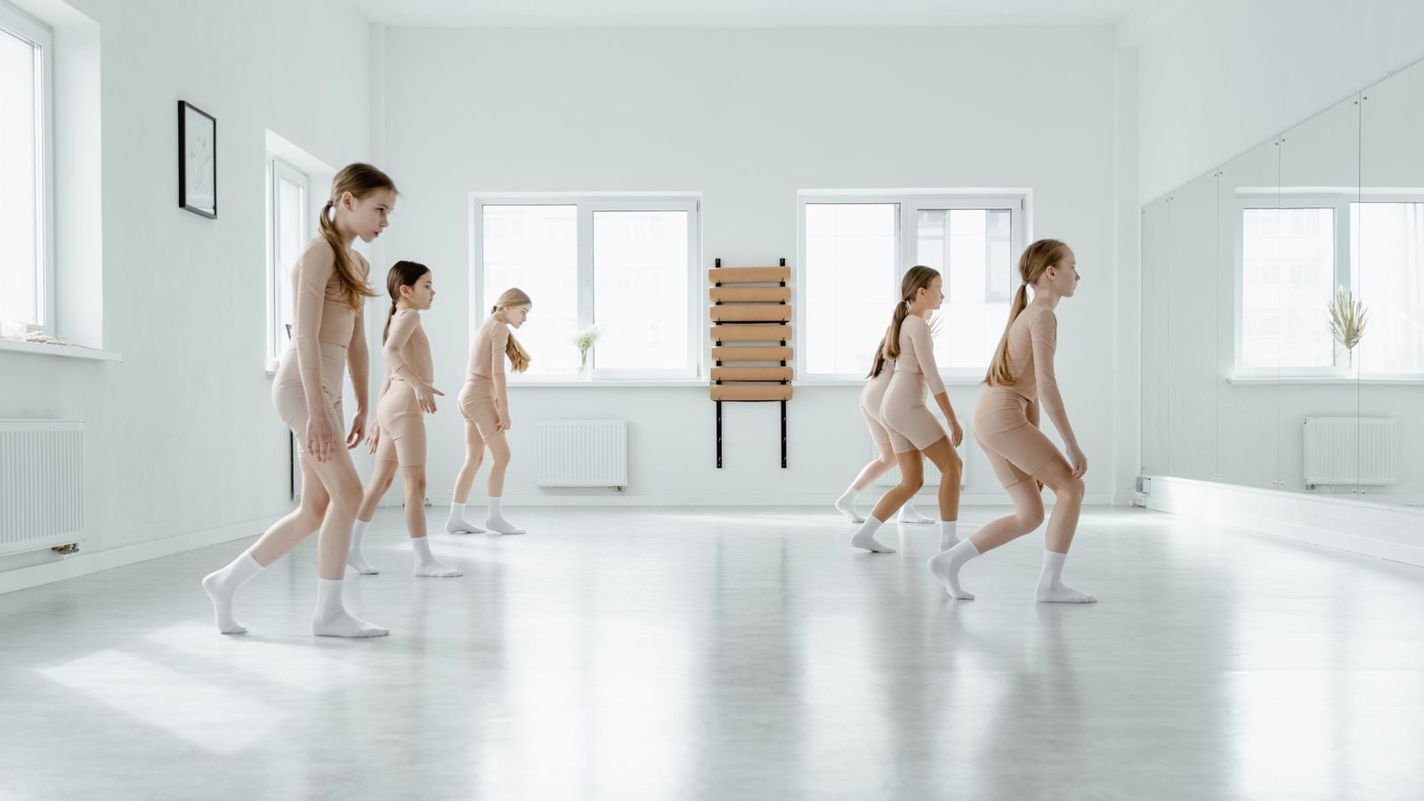 Dance class practicing a routine in a studio with mirrors