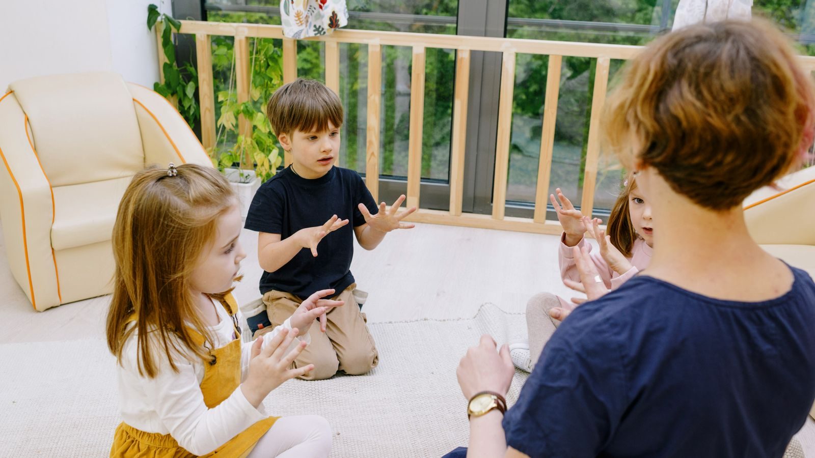 Teacher counting on her fingers with young children in a bright classroom