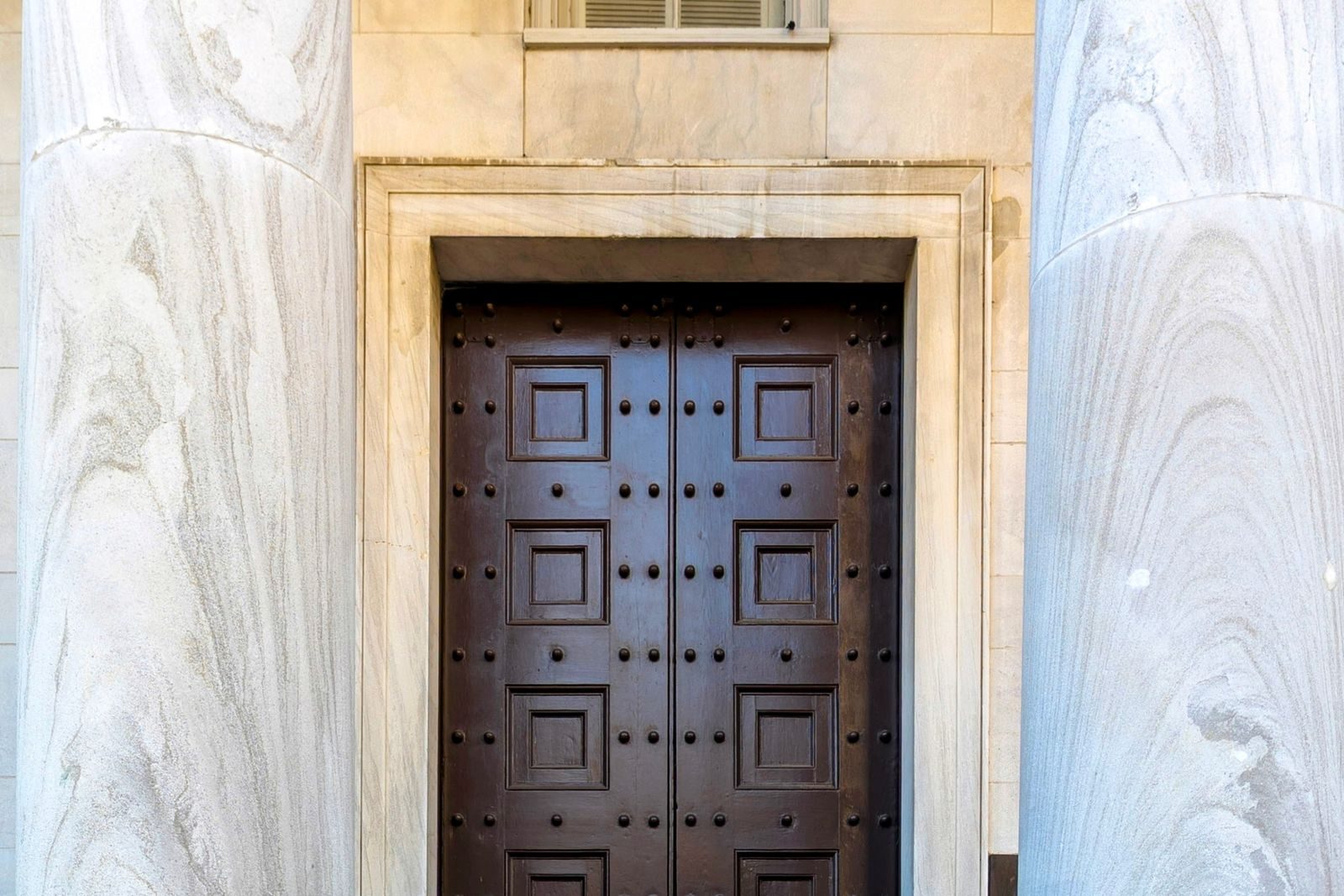 Heavy wooden courthouse doors between marble columns