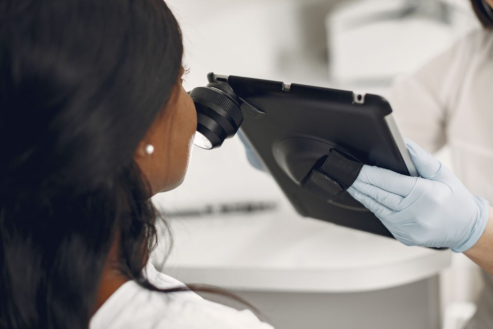 Dermatologist examining a patient with a digital dermatoscope mounted on a tablet