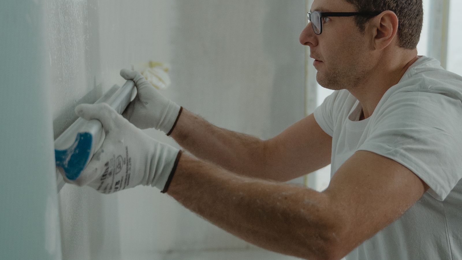 Drywall finisher skimming joint compound over a taped seam