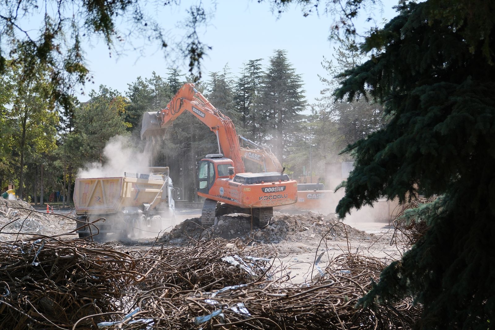Excavator loading cleared brush into a dump truck