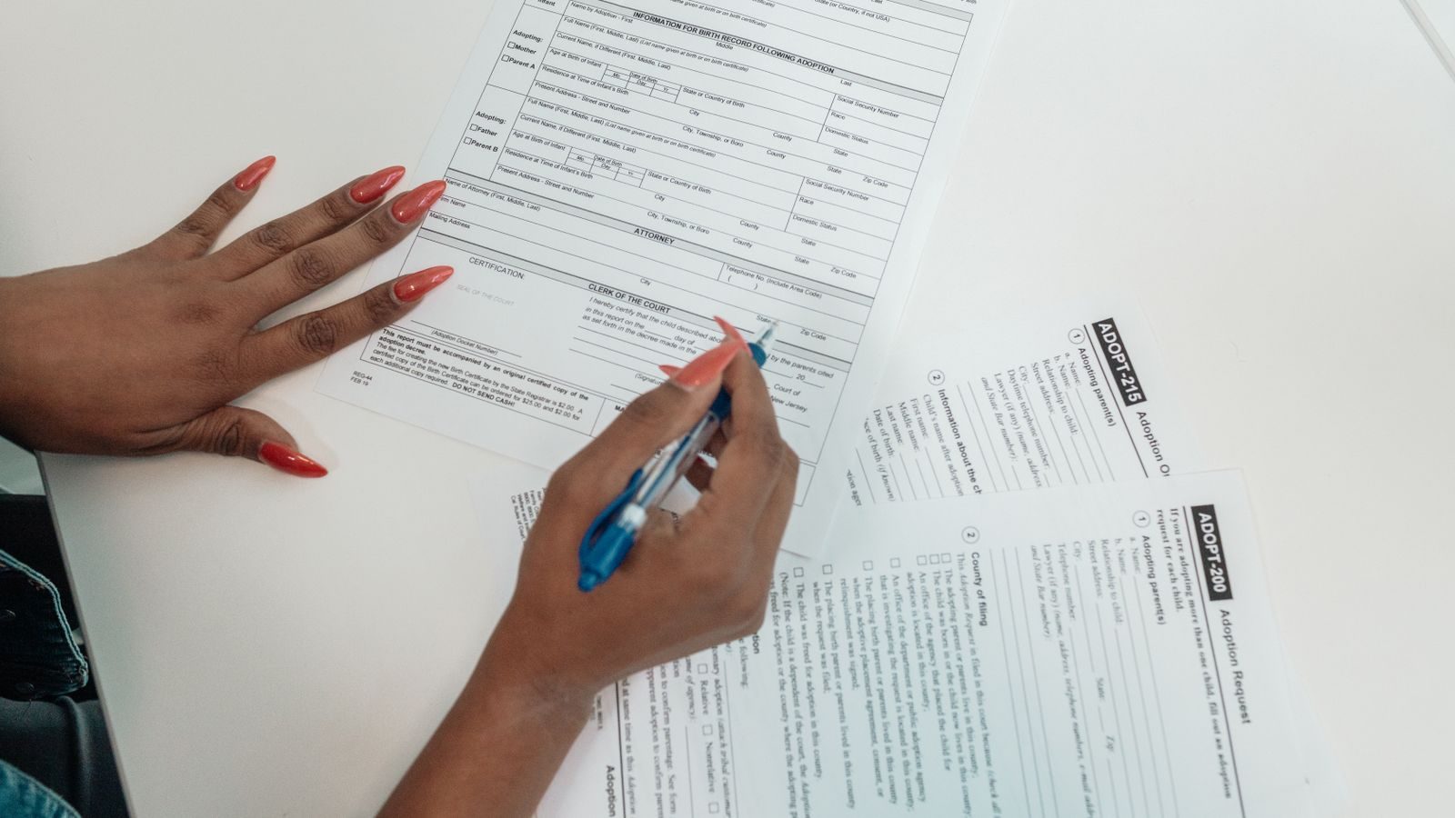 Hand filling in blank family court forms on a desk