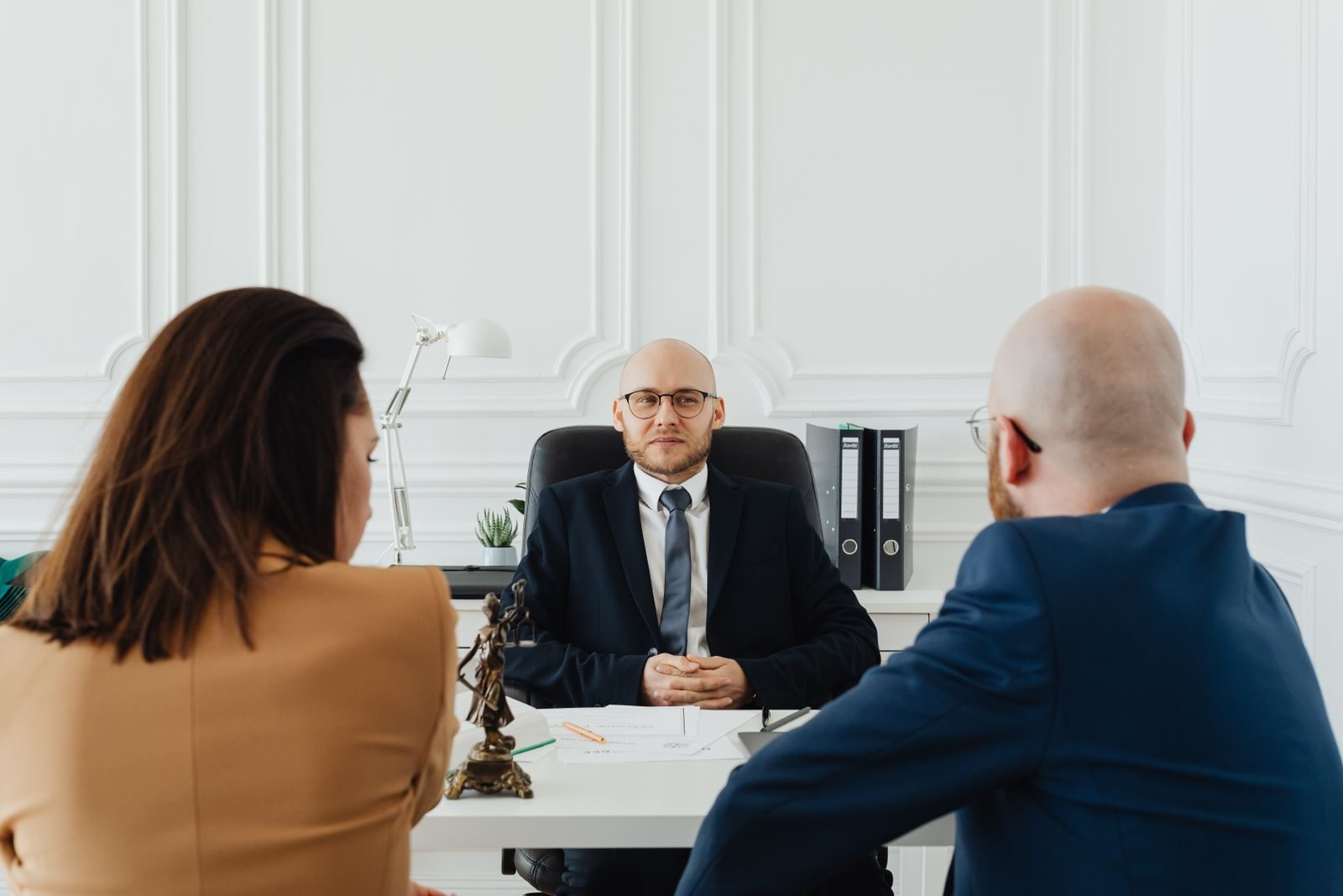 Couple seen from behind sitting across a desk from a family lawyer