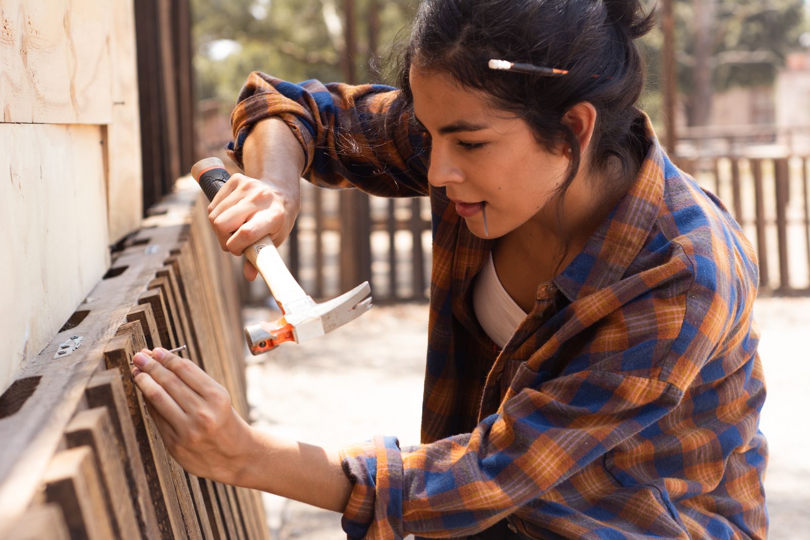 Carpenter hammering a board on a wooden fence