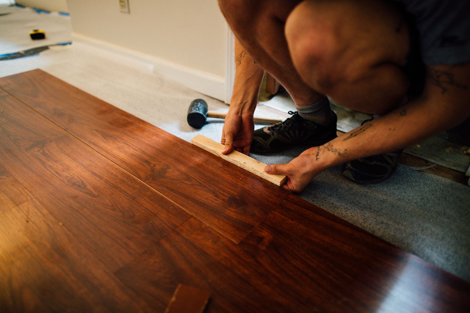 Installer laying plank flooring with a mallet