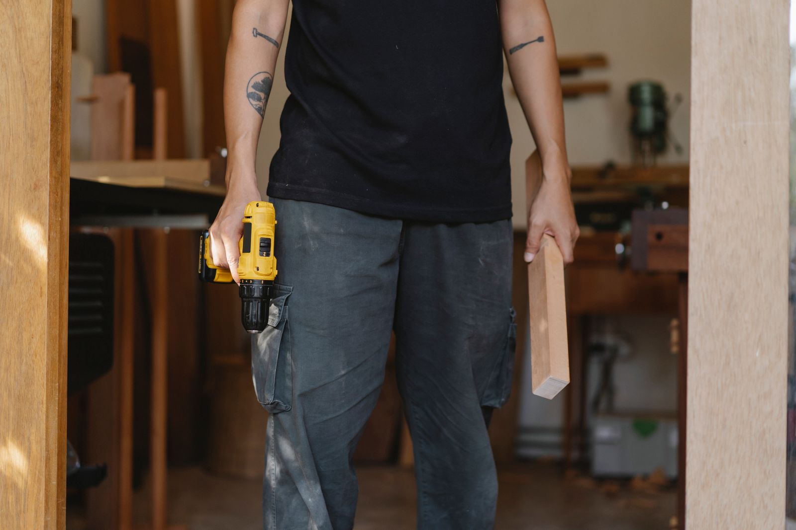 Handyman holding a cordless drill and a length of timber