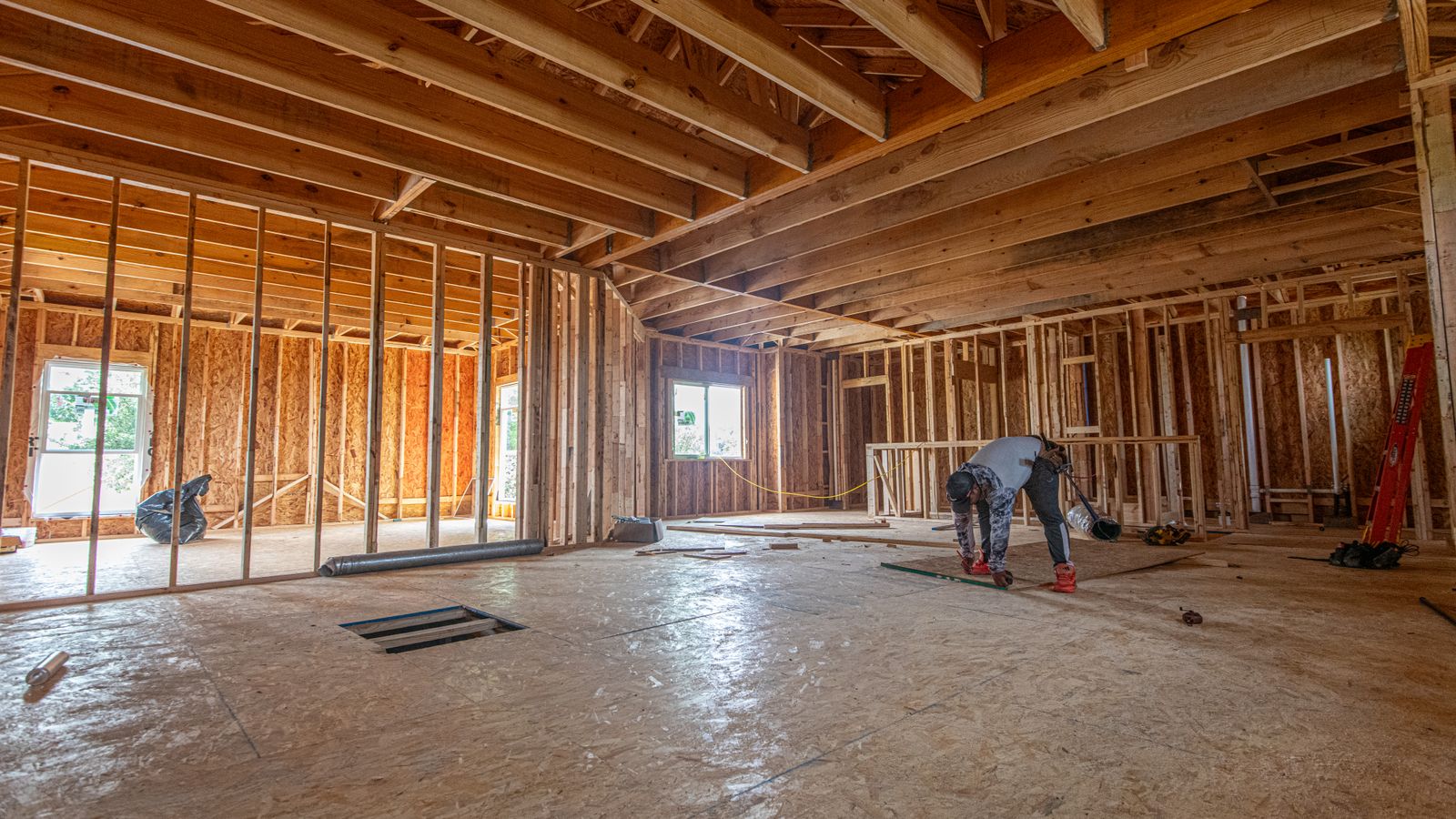 Interior framing of a new house with a carpenter working on the floor