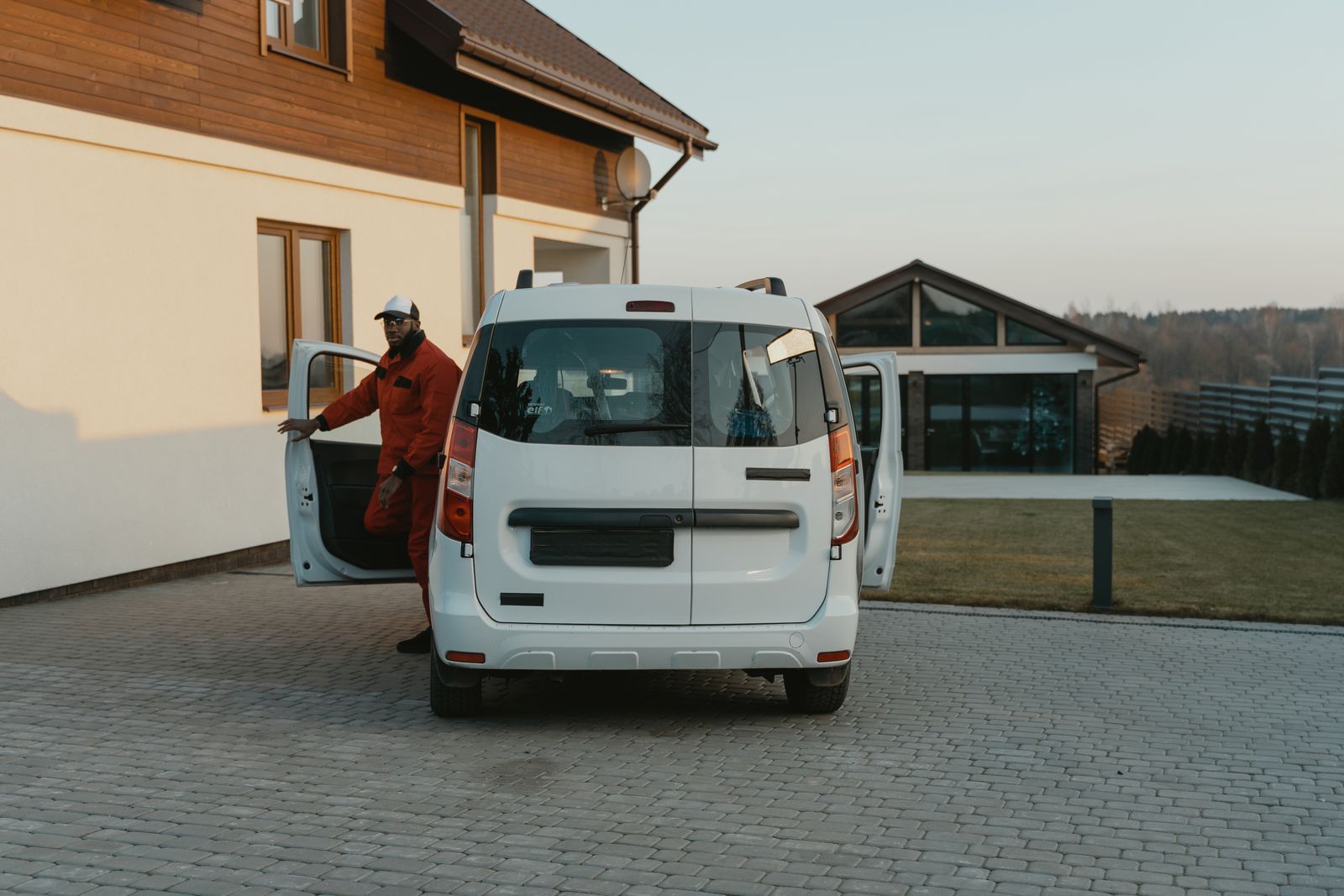 Home service technician stepping out of a work van in a residential driveway