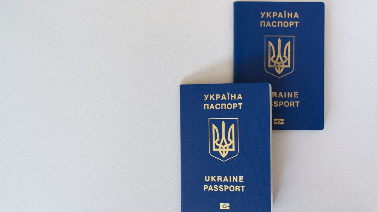 Two closed passports lying on a plain table