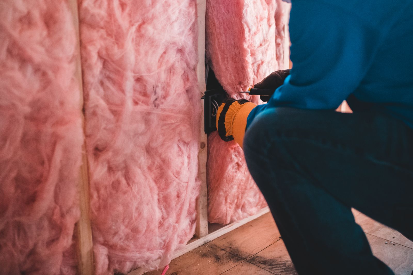 Worker fitting insulation batts between wall studs