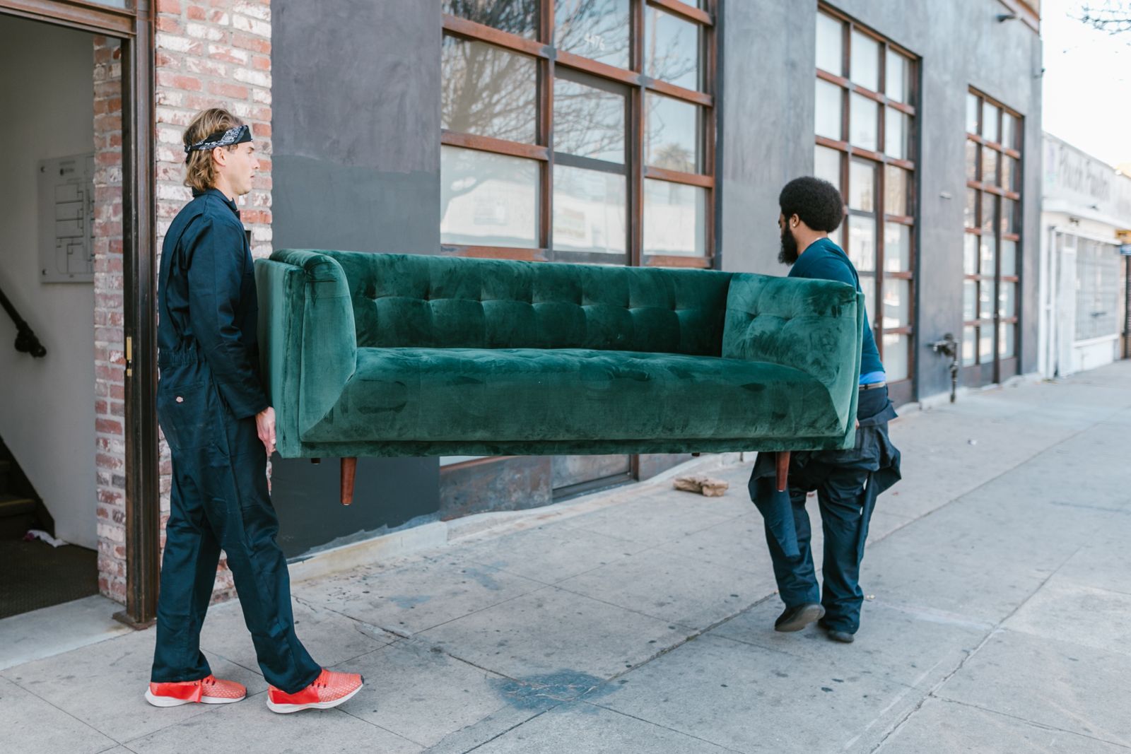 Two haulers carrying a sofa out to the street