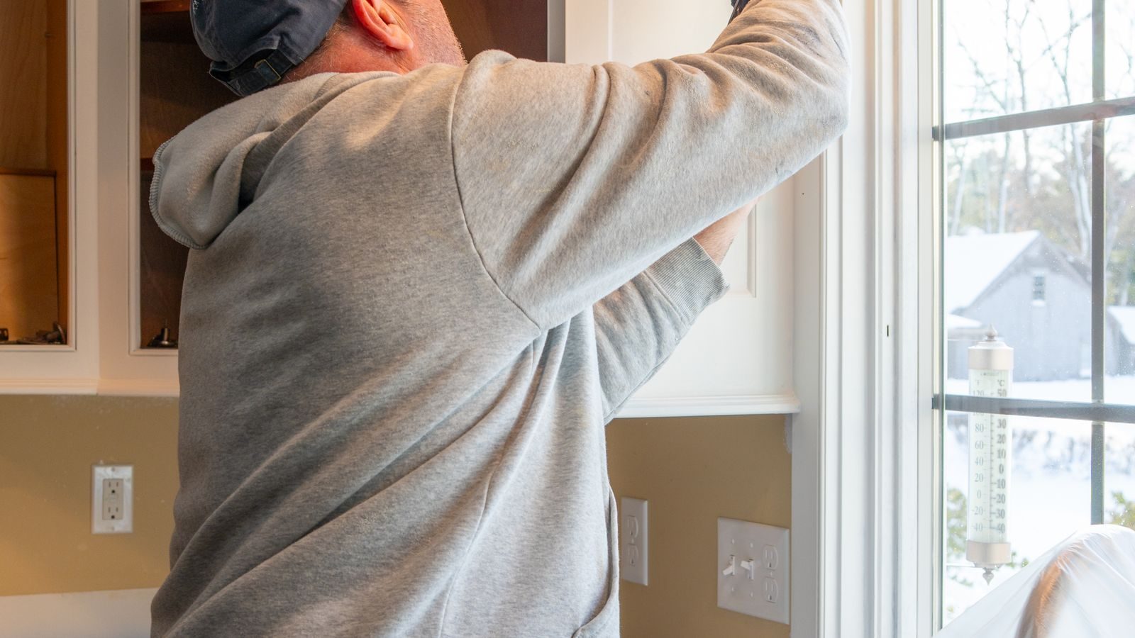 Remodeler caulking a new kitchen cabinet during installation