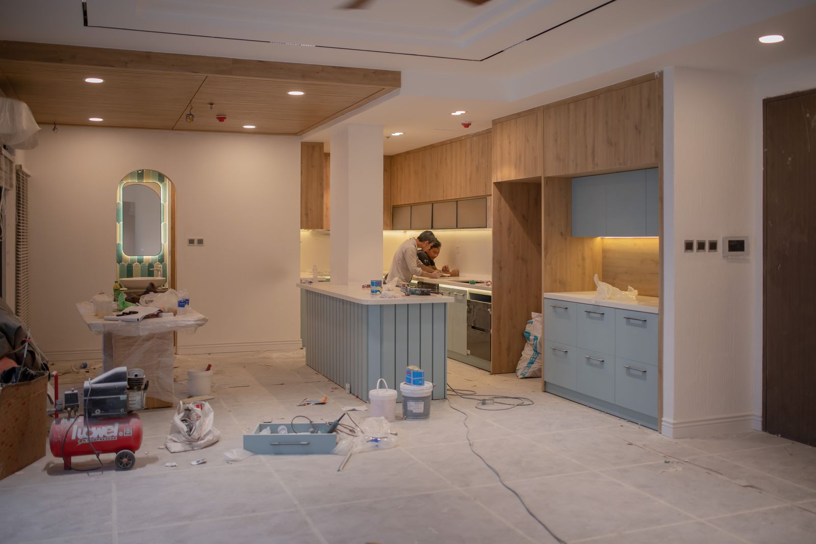 Kitchen under renovation with a worker and materials on site