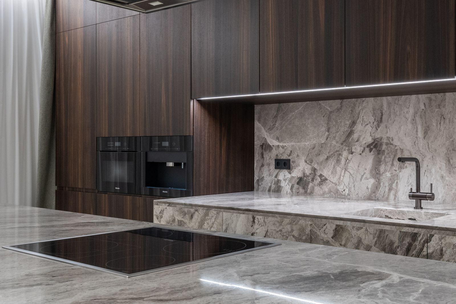 Modern kitchen with a stone backsplash and dark cabinetry
