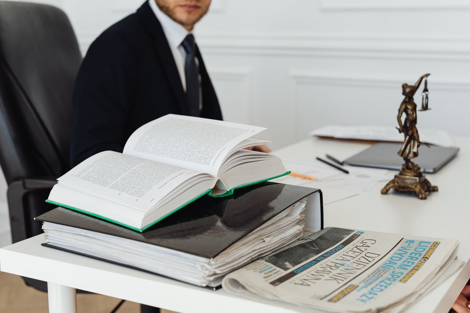 Attorney at a desk with legal books and a scales-of-justice figure