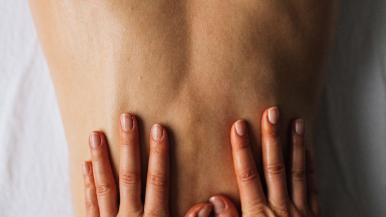 Therapist's hands working along a client's lower back