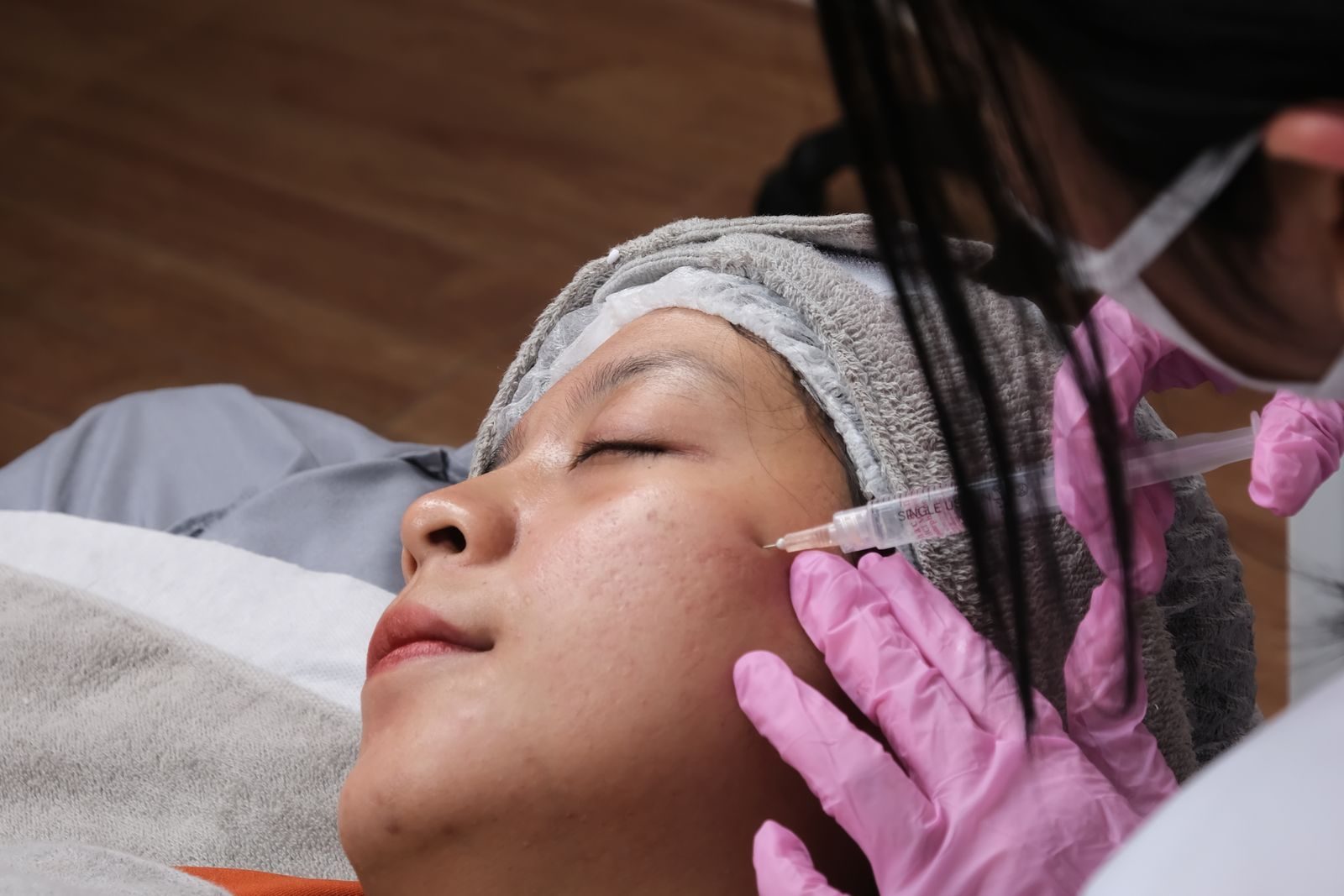 Provider in pink gloves giving a cosmetic injection to a patient in a treatment chair
