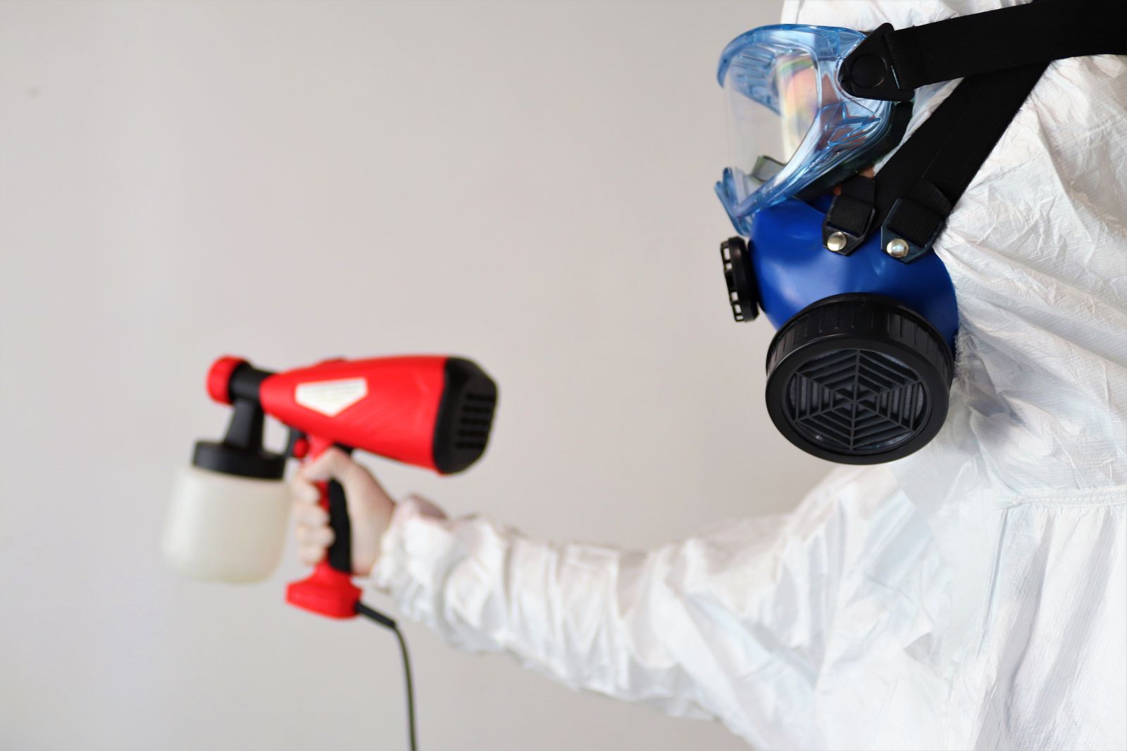 Remediation worker in a respirator holding a sprayer