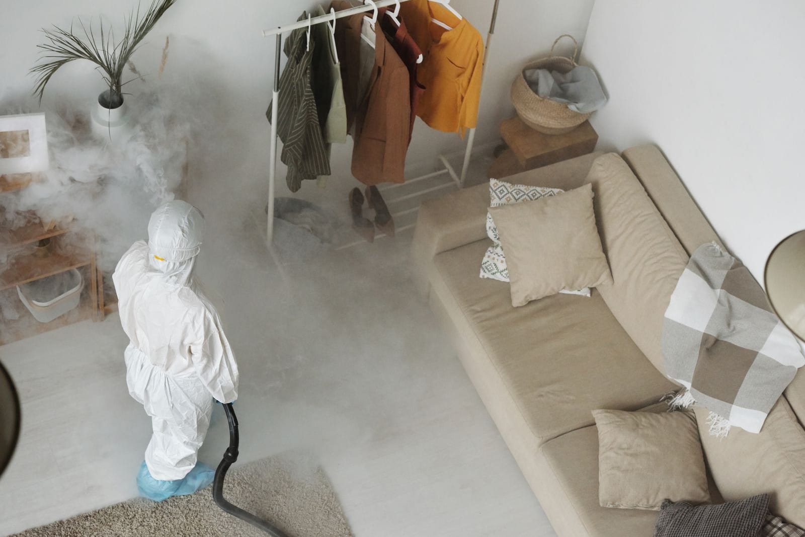 Pest control technician in protective coveralls fogging the interior of a home
