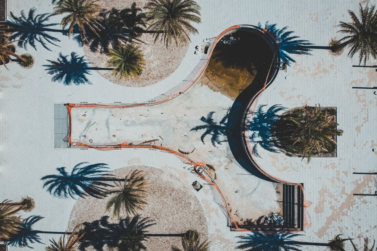 Aerial view of an empty backyard pool surrounded by palm trees