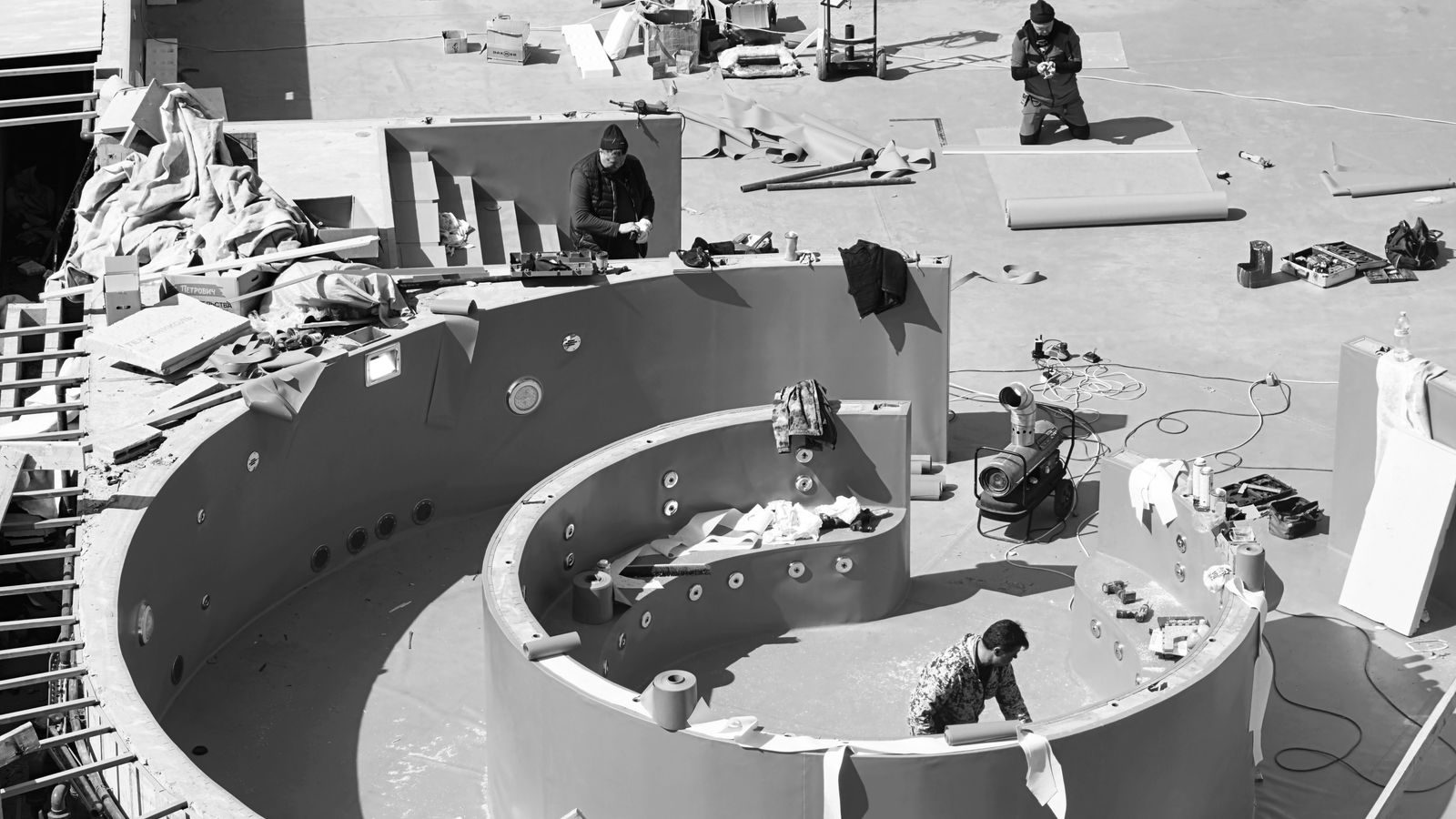 Crew working on a curved pool shell seen from above