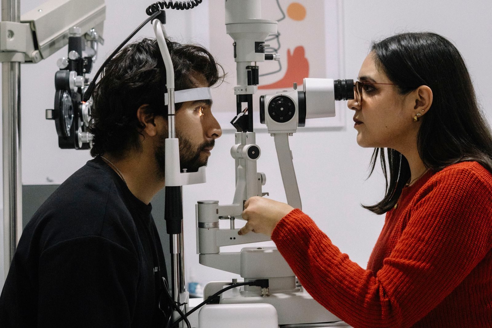 Optometrist examining a patient through a slit lamp during an eye exam