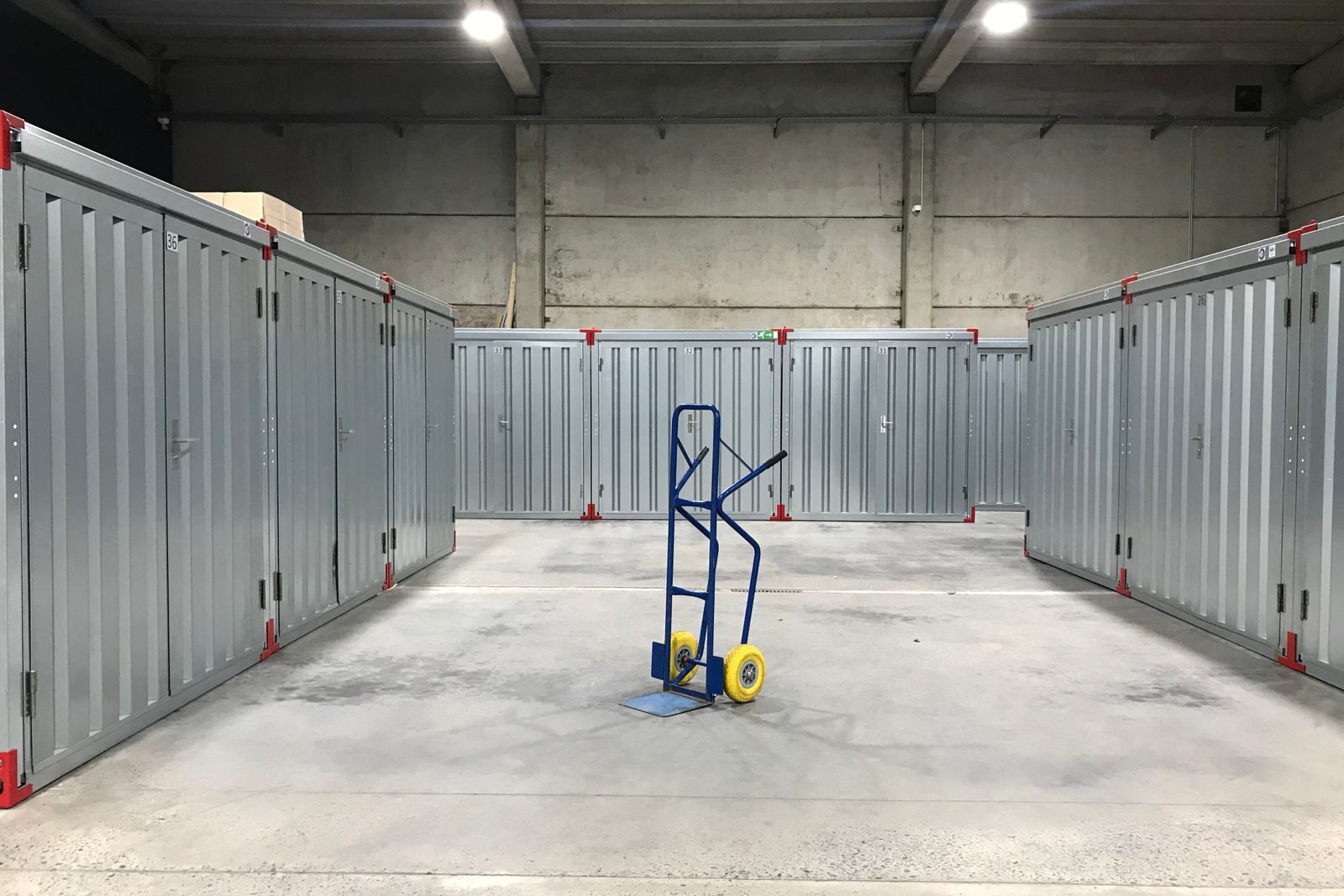 Indoor self storage corridor lined with steel unit doors and a hand truck