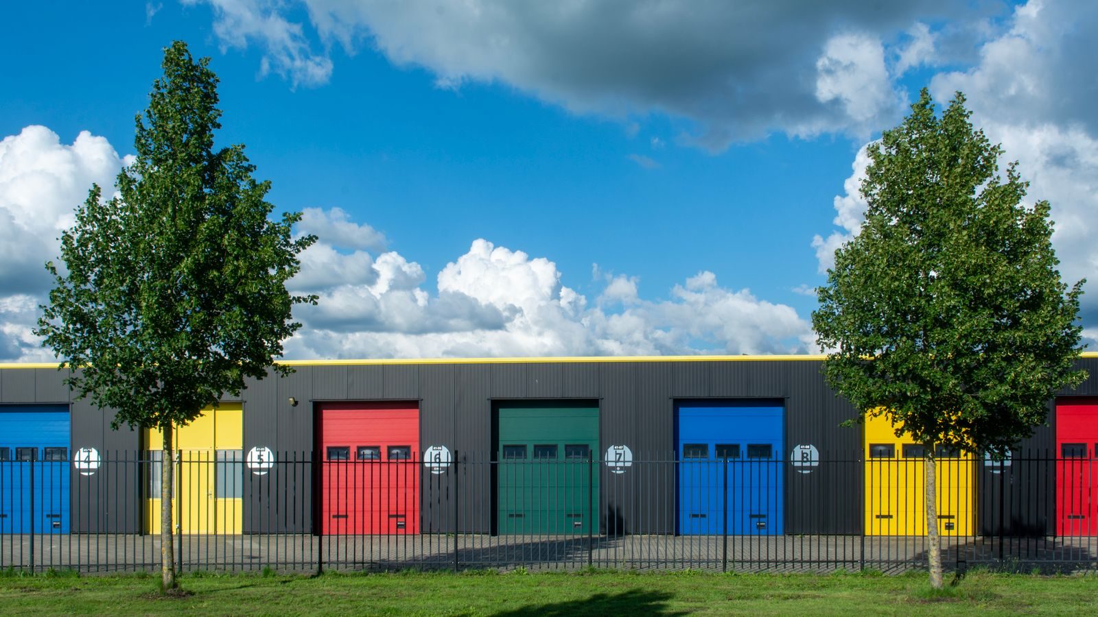Row of colourful drive-up self storage doors under a blue sky