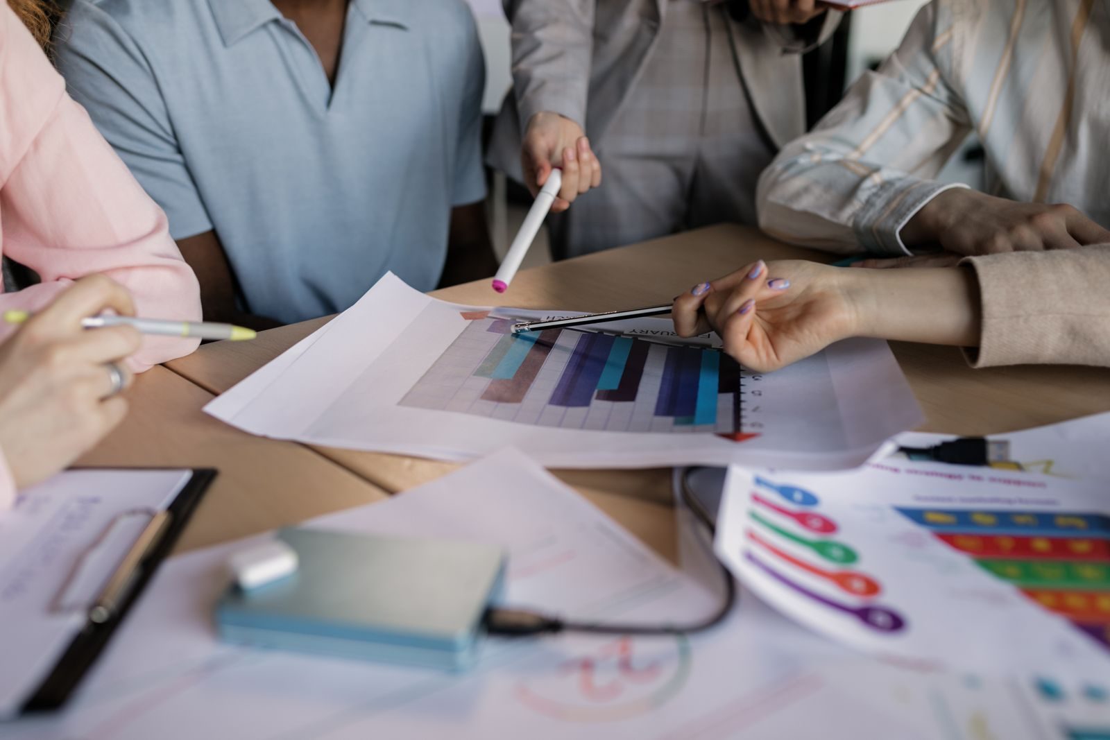 Franchise marketing team planning around printed charts on a meeting table