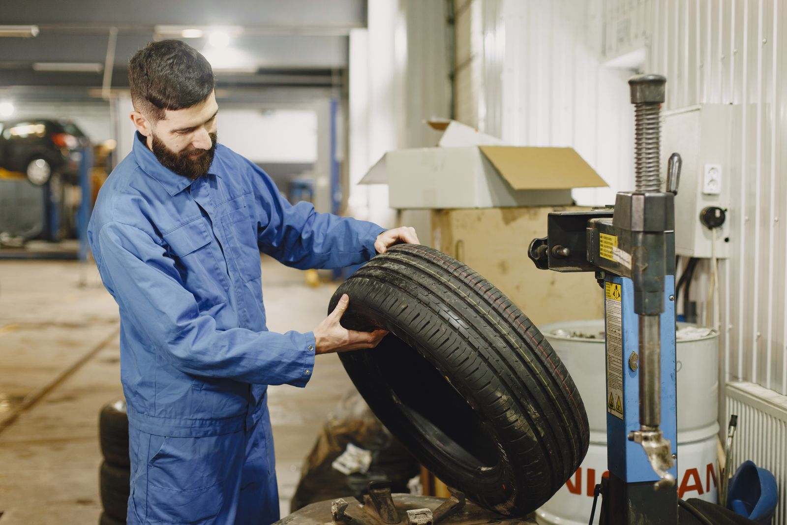 Mechanic in a blue uniform mounting a tire on a balancing machine