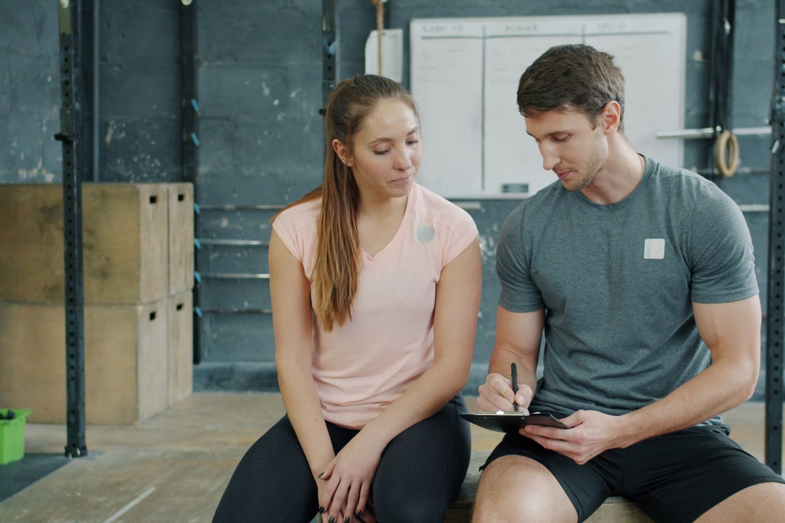 Personal trainer going through a training plan on a clipboard with a client in a gym
