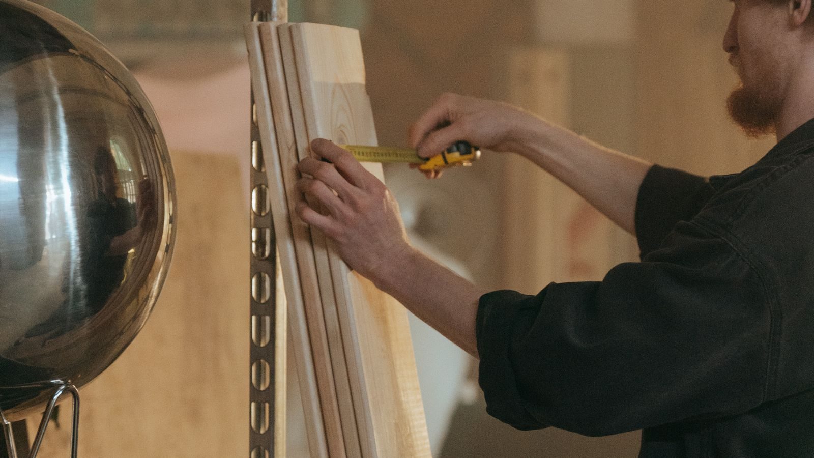 Carpenter measuring a length of trim against a wall with a tape measure
