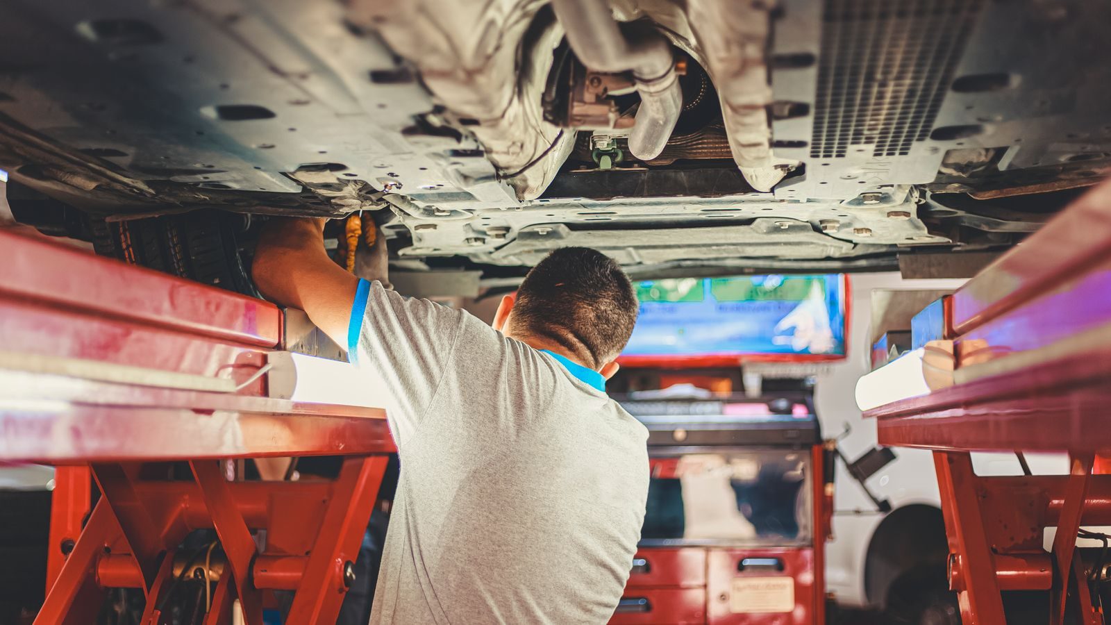 Technician working beneath a car raised on a lift