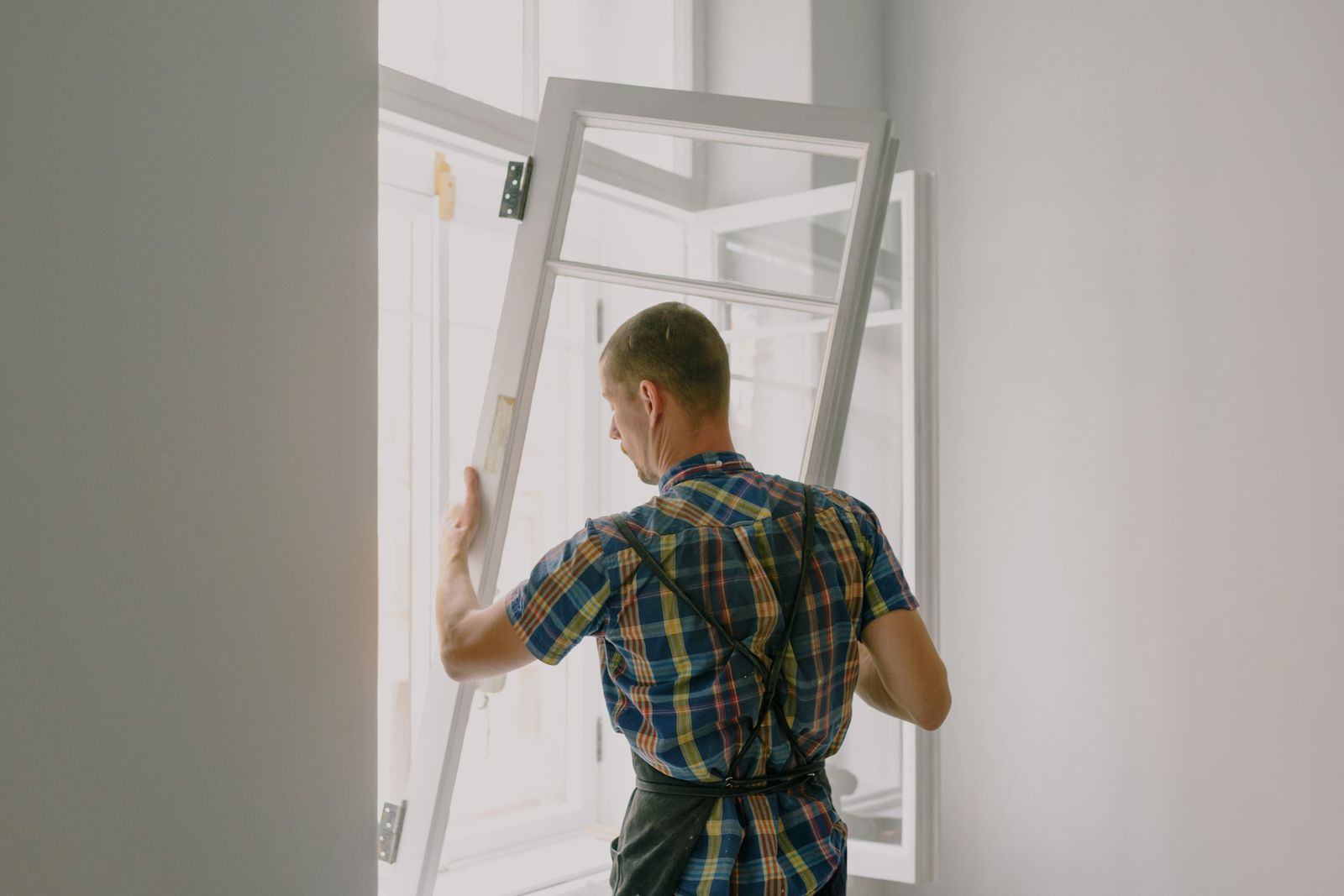 Installer fitting a new window in a bright room
